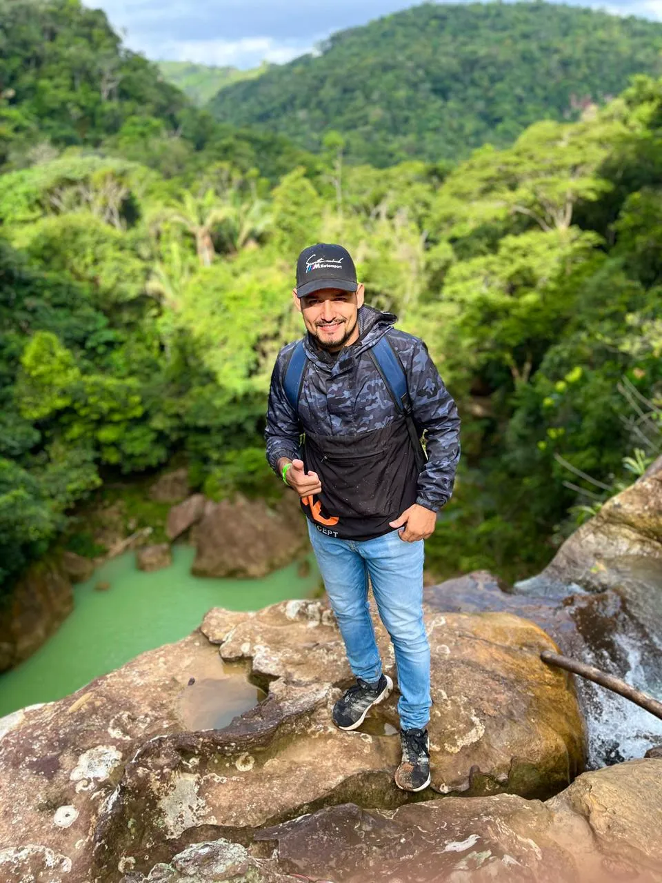 Excursionista junto a una cascada rodeada de vegetación